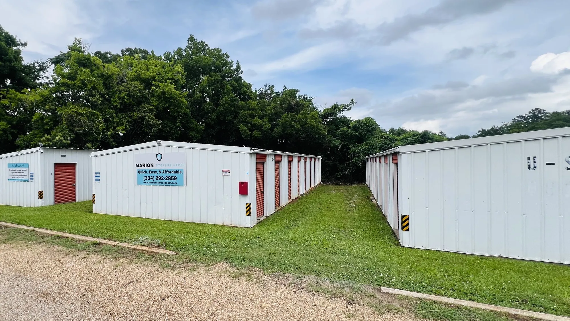Marion Storage Depot in Marion, Alabama: white storage buildings with red roll-up doors and the facility sign board